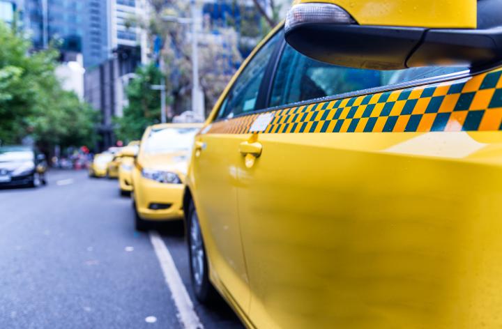 Image of a taxi sitting in a taxi rank in a metropolitan street