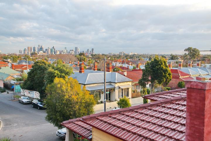 Image showing Melbourne on the horizon, with a suburb sprawling before it. A red roof is in the foreground.