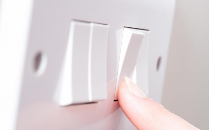 Image of a finger pressing a light switch on a wall