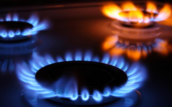 A close-up photo showing three gas burners turned on. Two gas burners are burning blue, while a third is burning orange. 