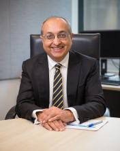 Commissioner Sitesh Bhojani sitting at a desk looking at the camera, smiling.